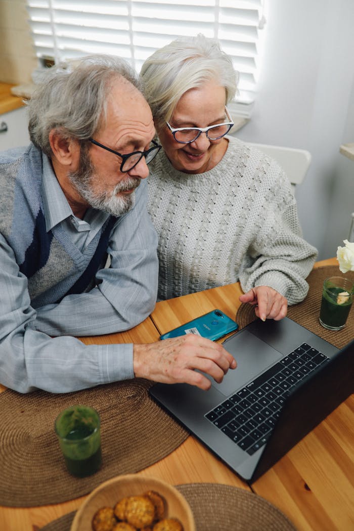 Elderly couple enjoying technology and sharing a moment at home with a laptop.