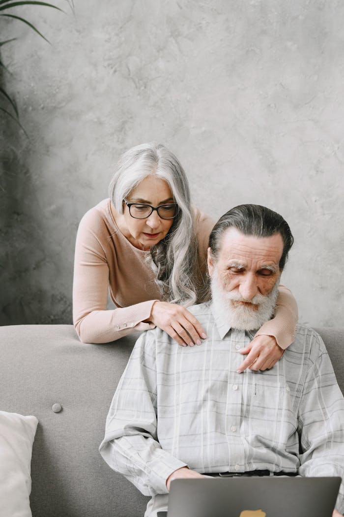 Elderly couple exploring technology on a cozy couch at home.